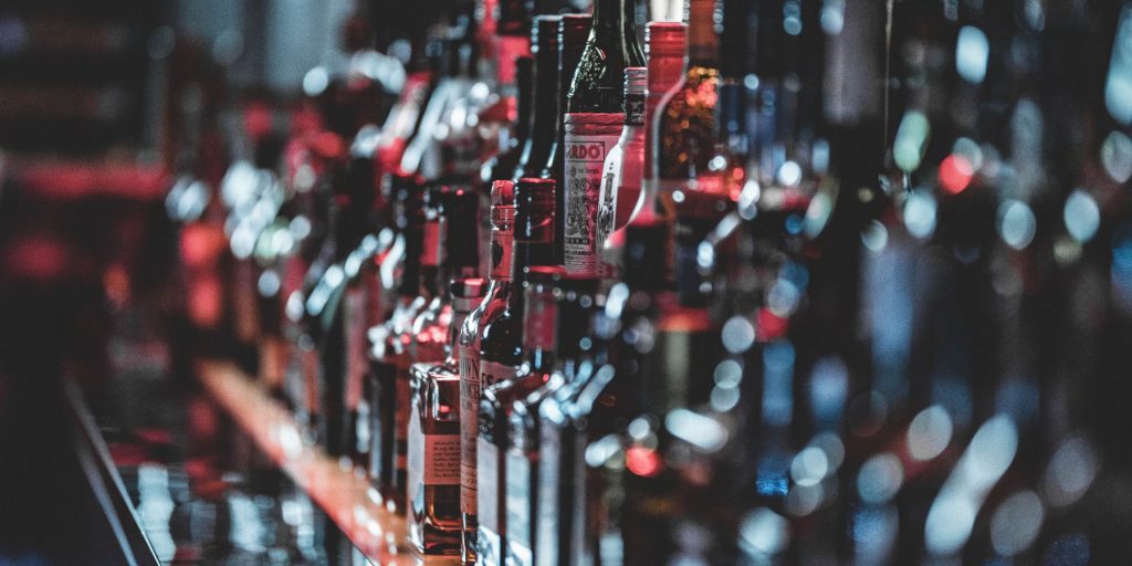 A side view of a row of liquor bottles on a shelf in a slightly moody setting