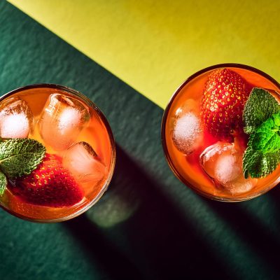 Overhead shot of Wray and Nephew rum cocktails on a yellow and green surface