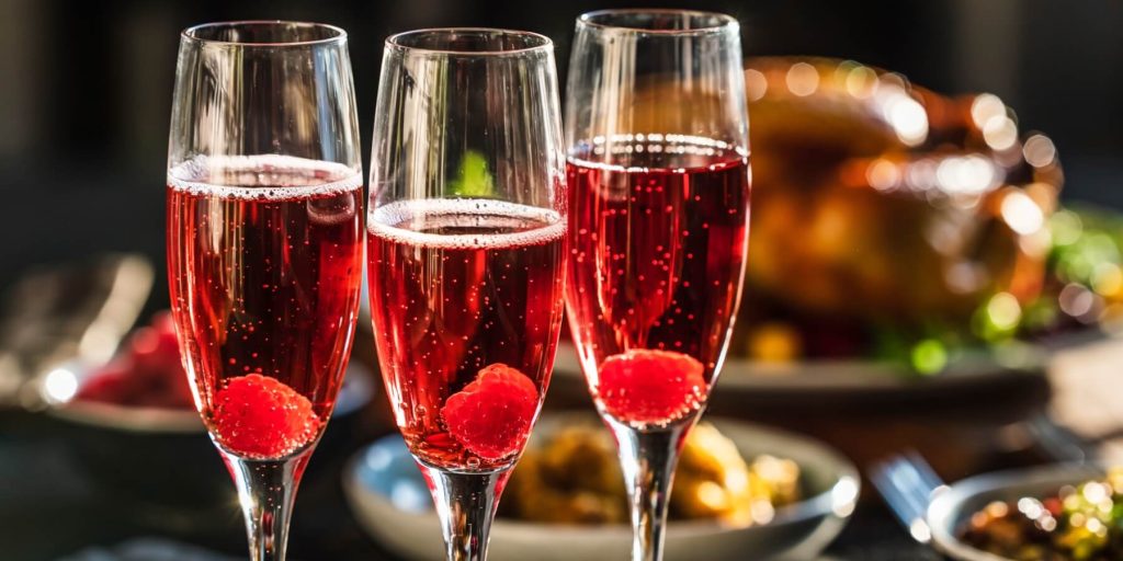 Three Kir Royale cocktails in flute glasses, Thanksgiving lunch table setting 