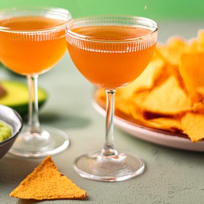 Two Naked and Famous Cinco de Mayo cocktails served with nachos and guacamole