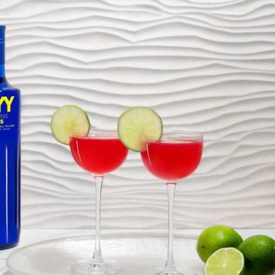 A close-up shot of a SKYY Vodka bottle with a strong shadow cast on a neutral wall, emphasizing the brand’s iconic blue glass design.