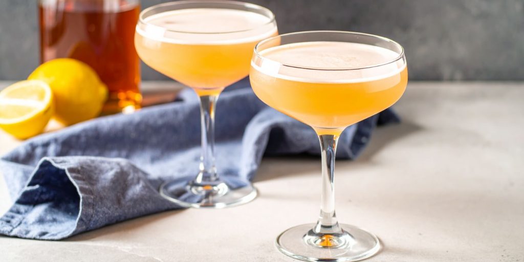 Two Old Vermont cocktails in coupe glasses on a white marble kitchen counter